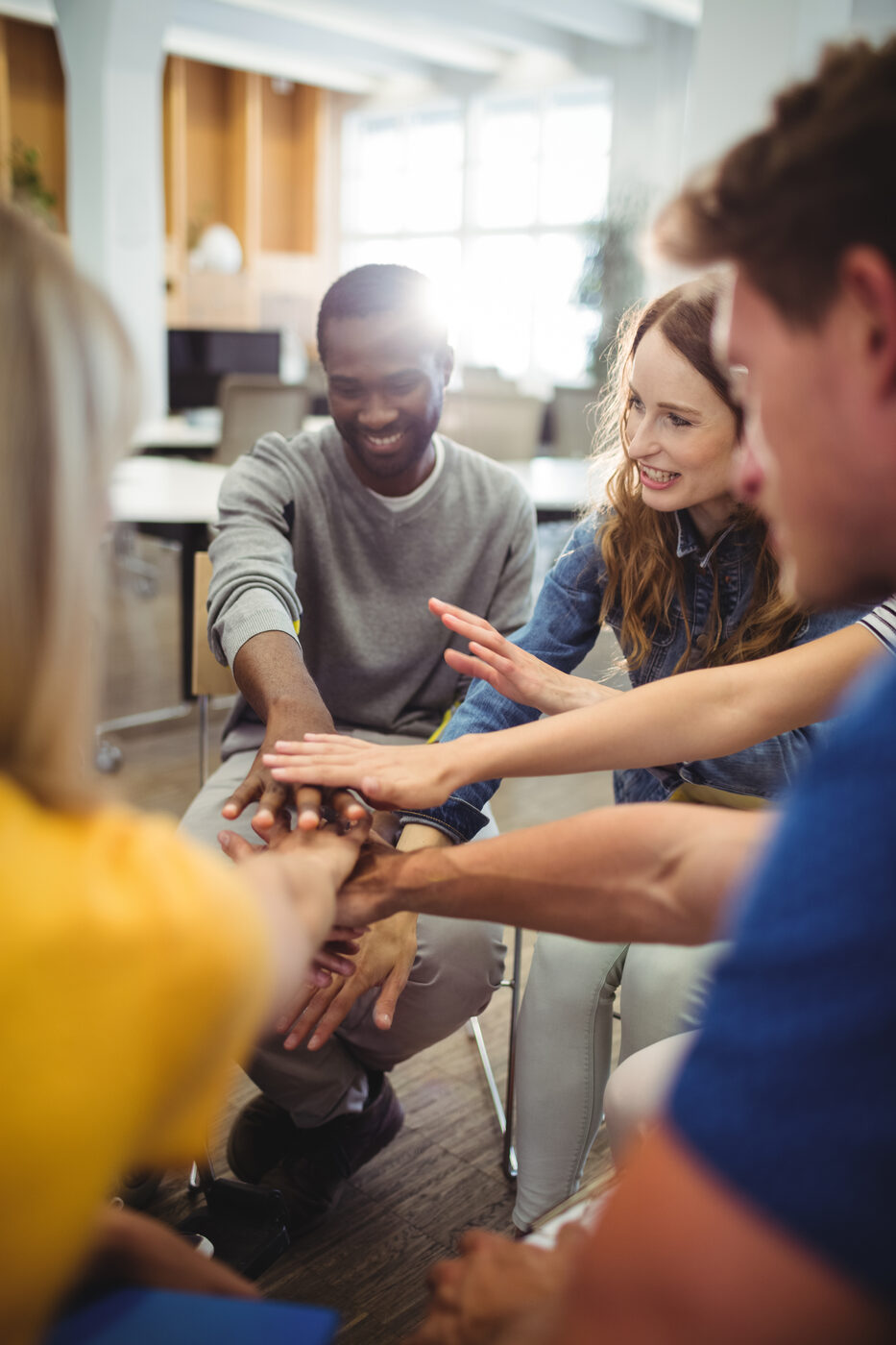 Équipe qui se donne un high five après une animation de cohésion d'équipe au bureau